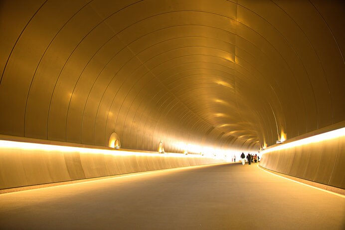 美術館へと続くスタイリッシュなトンネルは、先が見えないよう緩やかなカーブを描き、来場者の期待感を高める