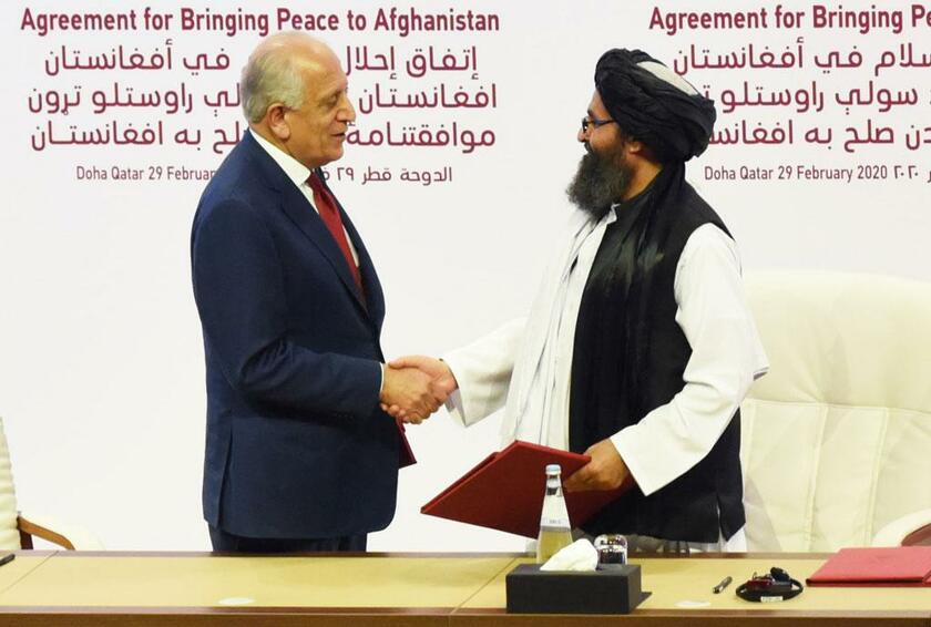 アフガニスタン駐留米軍の撤退に向けた合意に署名し、握手する米国のカリルザード和平担当特使（左）とタリバーン政治部門トップのバラダル幹部／２月２９日、ドーハ　（ｃ）朝日新聞社
