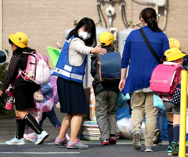 千葉県松戸市で地域ボランティアが見守る中、登校する児童と保護者　（ｃ）朝日新聞社