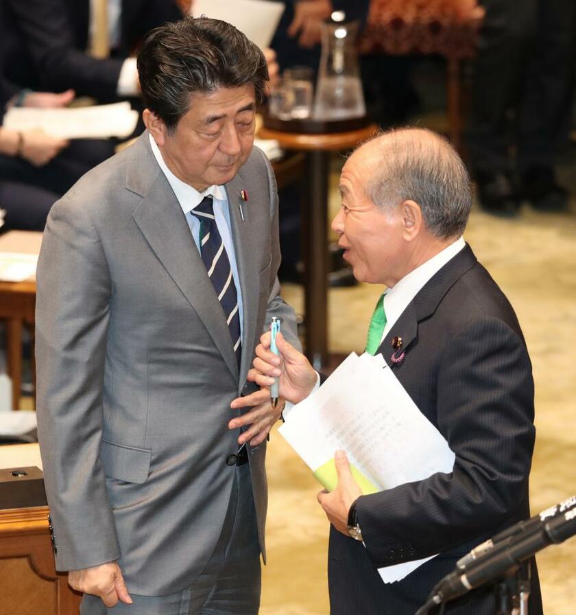 安倍晋三首相（当時、左）と言葉を交わす日本維新の会の鈴木宗男参院議員＝2020年1月30日