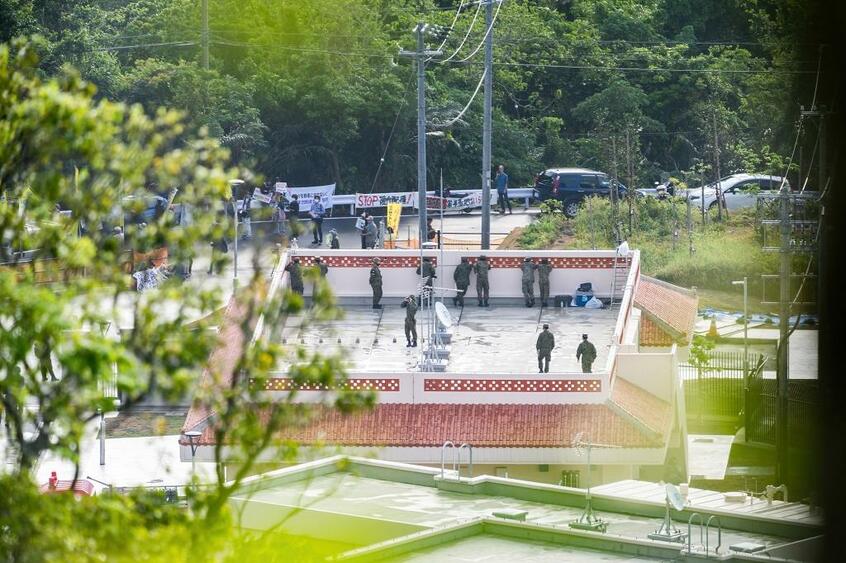 石垣駐屯地の警衛所屋上から、ゲート前で抗議する人たちをカメラやビデオで撮影したり双眼鏡で確認したりする自衛隊員たち＝3月16日午前8時50分ごろ（八重山毎日新聞提供）
