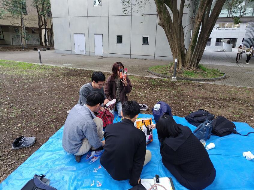 新歓鍋パーティー会場のブルーシートに、会の“常連”や新入生が集まってきた。写真を撮らせてほしいとお願いすると、いっせいに顔を隠す一同