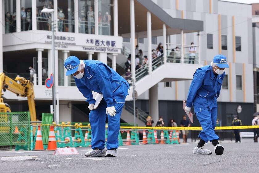 安倍晋三元首相が銃撃された現場付近を調べる捜査員ら＝２０２２年７月８日