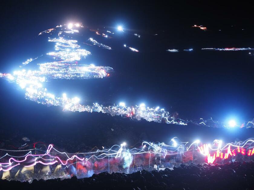 深夜から早朝、富士山の山頂付近は「頂上でご来光」を目指す人で混雑し、ヘッドランプの列がはるか下まで続く。２０１８年８月１３日午前３時、吉田・須走口山頂から撮影（写真：小岩井大輔さん提供）