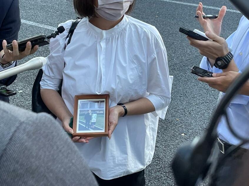 赤木俊夫さんの遺影を手にピンクのマスク姿の雅子さん（筆者提供）