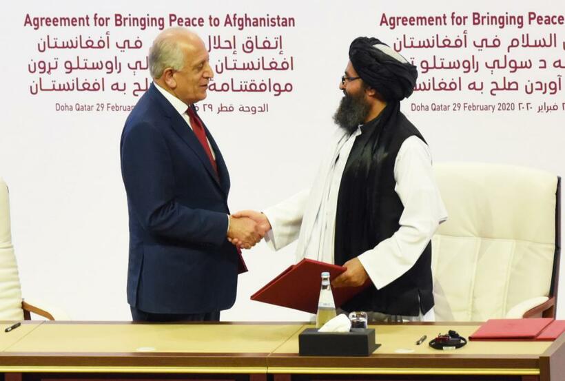 アフガニスタン駐留米軍の撤退に向けた合意に署名し、握手する米国のカリルザード和平担当特使（左）とタリバーン政治部門トップのバラダル幹部／２月２９日、ドーハ　（ｃ）朝日新聞社