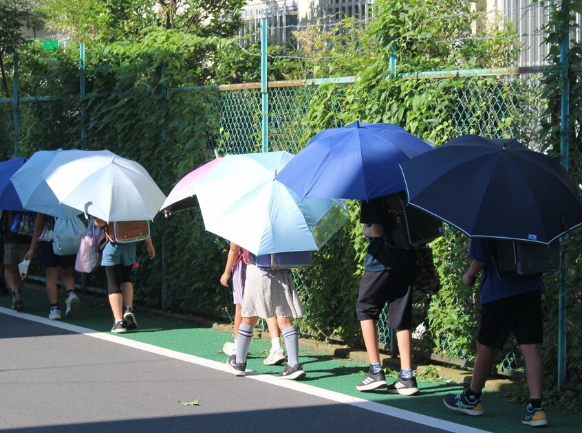栃木県壬生町で日傘を差して登校する児童たち。子どもの皮膚は薄く、紫外線の影響を受けやすい。日傘は暑さだけでなく、日焼け対策にもなる。(photo栃木県壬生町教育委員会提供)